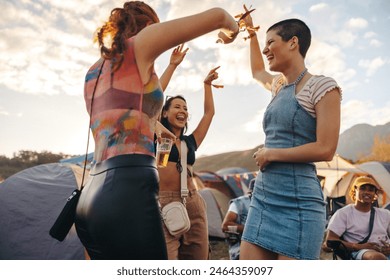 세 명의 젊은 여자 친구가 함께 춤추고 축하하며 유대감을 형성하고 소중한 추억을 만드는 음악 축제의 전염성 있는 에너지에 재미를 느낀다. 사진은 의도적인 35mm 필름 알갱이를 가지고 있습니다 스톡 사진
