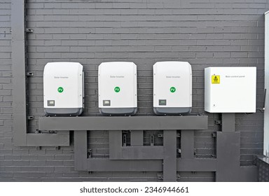 Three commercial size solar inverters and a control panel on a brick wall 库存照片