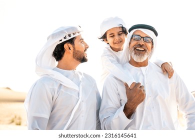 Three generation family making a safari in the desert of Dubai wearing white kandura outfit. Grandfather, son and grandson spending time together in the nature. Arkistovalokuva