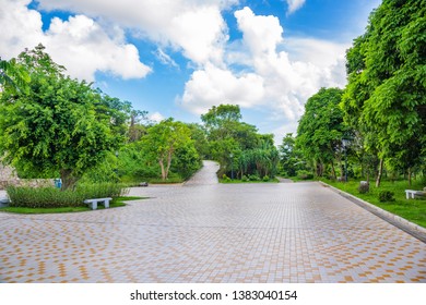 The tile floor of the outdoor park square is under the blue sky and white clouds. Foto stock
