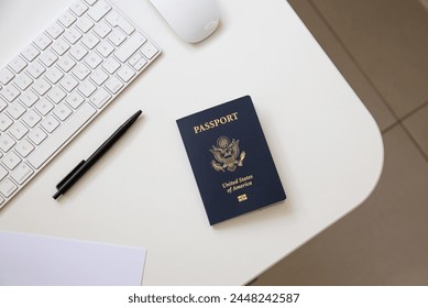 Vista superior de un pasaporte americano sobre una mesa blanca, con una bandeja negra, un teclado y un ratón de ordenador Foto de stock
