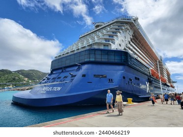 イギリス領ヴァージン諸島トルトラ - 2024年2月22日 – ターミナルの入り口でセレブリティ・リフレクションのクルーズ船の隣を歩く乗客の写真素材