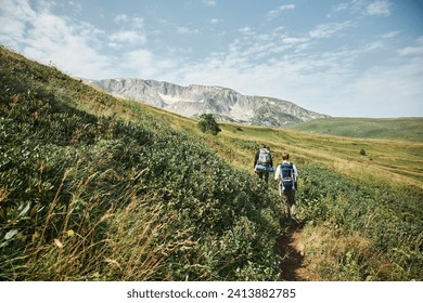 Стоковая фотография: A tourist walks along a trail in the mountains. A high-altitude region. The Caucasus Mountains. Tourism and mountain climbing