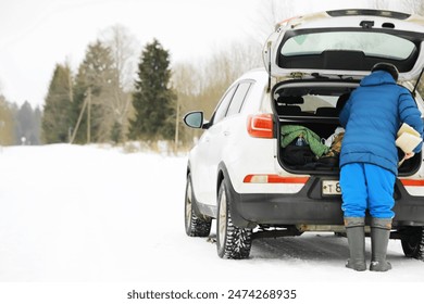 Traveler Loading SUV Trunk in Snowy Winter Landscape Foto stock
