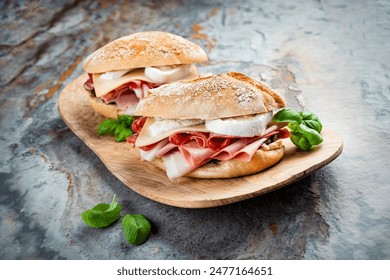 Traditional New Orleans muffaletta sandwiches with mortadella, salami and provolone cheese served in an Italian ciabatta bread as close-up on a wooden design cutting board Stock-foto