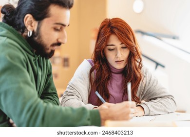 Two focused students writing notes together in a classroom setting, collaborative study, young adults learning, academic teamwork, engaged and concentrated educational environment Stock-foto