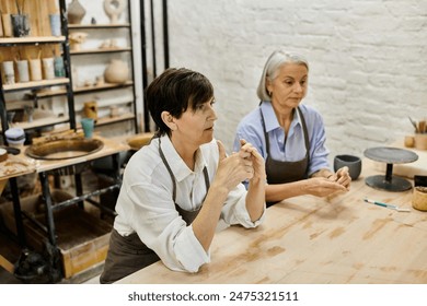 陶芸工房で二人の成熟した女性がプロジェクトに一緒に取り組んでいます。の写真素材