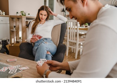 Two people man and woman young couple husband and wife brother and sister or boyfriend and girlfriend playing cards at home in bright day real people leisure games concept having fun copy space ภาพถ่ายสต็อก