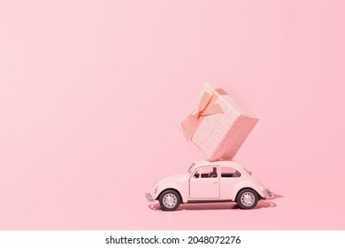 Ufa, Russia - September 20, 2021: Pink retro toy car delivering gift box on pink background. International Happy Women's Day. Valentine's day holiday celebrationのエディトリアル写真素材