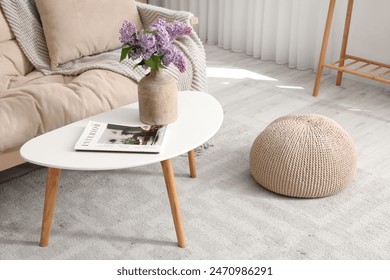 Vase with lilac flowers and magazine on coffee table in living room: zdjęcie stockowe