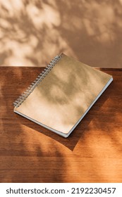 vintage notebook on table with leaves shadows on it.: stockfoto
