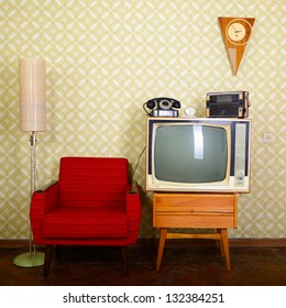 Vintage room with wallpaper, old fashioned armchair, retro tv, phone, clocks, radio player and standart lamp Stock Photo