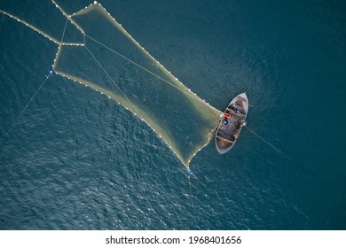 Vintage wooden boat in coral sea. Boat drone photo. A fisherman on a fishing boat is casting a net for catching fish. Foto stock