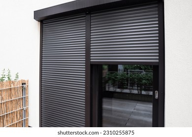 View of building with big windows and black roller shutters outdoors Foto stock