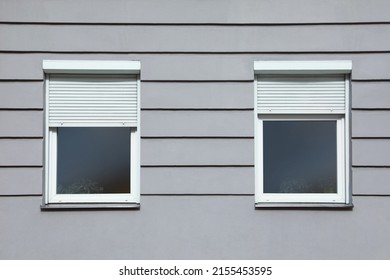 Wall of grey stone building with windows and rolling shutters Foto stock