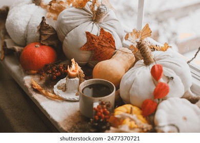 Warm cup of tea, pumpkins, autumn leaves, candle and woolen scarf on windowsill. Autumn hygge still life. Happy Thanksgiving. Hello fall Arkistovalokuva