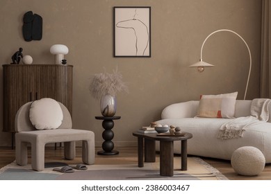 Warm and cozy composition of living room interior with mock up poster frame, boucle sofa, gray armchair, wooden sideboard, vase with dried flowers and personal accessories. Home decor. Template. Foto Stock