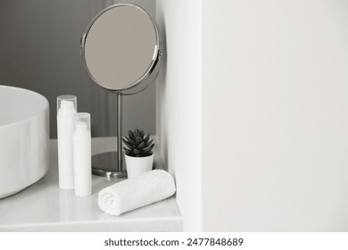 White cream round plastic tubes, small table mirror, towel, succulent plant in a pot against the vessel sink on the marble surface. Stockfoto