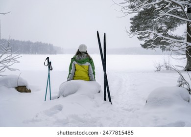 Woman taking break and sitting on rock in winter forest Foto stock