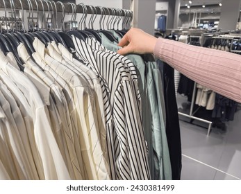 Eine Frau sucht sich in einem Bekleidungsgeschäft ein Hemd aus.  Klassische Damenmode Kleidung – Stockfoto