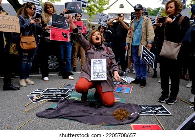 A woman cuts her hair during a demonstration in front of the Iranian embassy in Brussels, Belgium on Sept. 23, 2022, following the death of Mahsa Amini. Foto stock editoriale