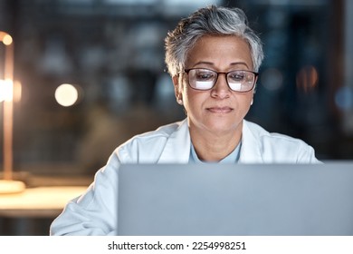 Woman, doctor and laptop in office at night at workplace, hospital or desk for medical career vision. Healthcare expert, dark clinic or focus for reading at computer, email or cancer research article 库存照片