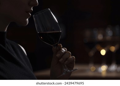 Woman with glass of red wine against blurred background, closeup. Space for text