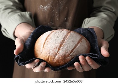 Woman holding freshly baked bread on black background, closeup Foto stock