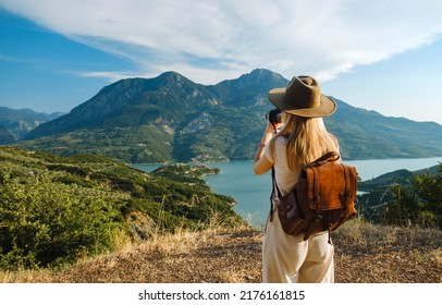 Woman photographer with big backpack taking photo of mountains and blue lake. Travel and hobby concept: stockfoto