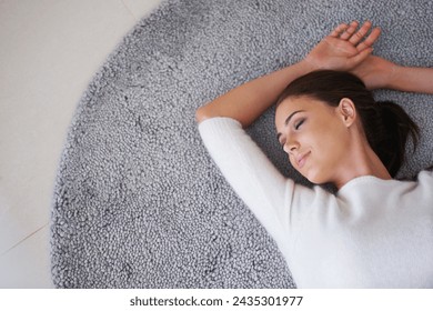 Woman, relax and sleeping with rug on floor above for break, peace or comfort at home. Top view of happy, young or tired female person lying on carpet or mat for peaceful rest in living room at house ภาพถ่ายสต็อก