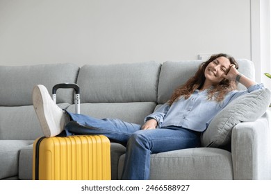 Woman resting in the living room of her house until it's time to go to the airport. Woman resting on the sofa waiting for her flight time. Woman on vacation has just arrived at the hotel. Arkistovalokuva