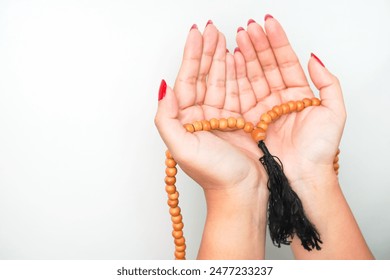 A woman's hand with bright red nail polish is making an open hand gesture and praying while holding prayer beads. Isolated on white background - cut out: stockfoto