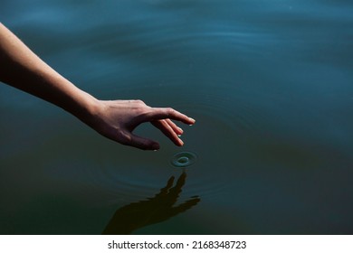 女性の手が池の水に優しく触れ、静けさをテーマにした水平の近い写真の写真素材