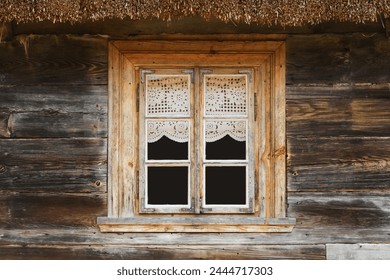 コテージハウスの木製の素朴な窓。レースのカーテンのガラスの窓の家。錆びた建築。ポーランドビンテージウォールのポドラシー地域。木の家の壁のファサード。茅葺き屋根。の写真素材