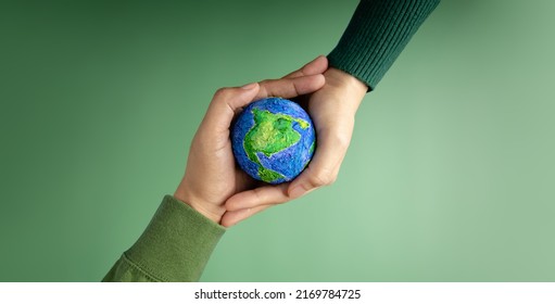 World Earth Day Concept. Green Energy, ESG, Renewable and Sustainable Resources. Environmental Care. Hands of People  Embracing a Handmade Globe. Protecting Planet Together. Top View: stockfoto