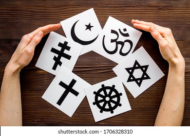 World religions concept. Hands hugs Christianity, Catholicism, Buddhism, Judaism, Islam symbols on wooden background top view Stock Photo
