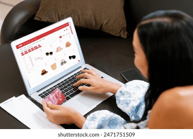 Young woman using laptop with credit card for internet banking, online shopping E commerce by online payment gateway at home. Modern and convenience online shopping with debit card. Blithe 库存照片