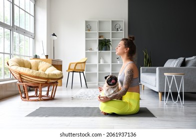 Young woman with cute pug dog meditating at home Stock fotografie