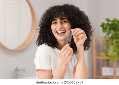 Mujer joven que sostiene las tiras blanqueadoras de los dientes en el baño Foto de stock