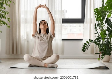 大きな窓の近くのヨガマットに座って瞑想している若い女性の写真素材