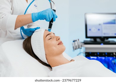 Young woman is relaxing getting vaccum facial hydro peeling procedure in beauty salon. Hardware face pores cleansing, close-up. Stockfotó
