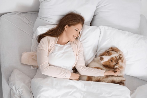 Jeune femme dormant avec un mignon chien australien Shepherd sur son lit à la maison : photo de stock