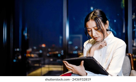 Young asian business woman working at the office at night with tablet, received bad news, business loss, unrequited love, depression and worry for distress, crying angry and afraid. sad expression. Foto Stock
