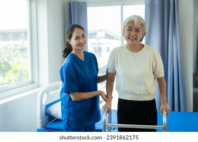 A young Asian nurse at a nursing home takes care of a senior woman. The attending physician provides physical therapy services for elderly patients to exercise for their health. 库存照片