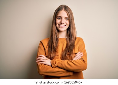 Joven mujer pelirroja vestida con suéter casual sobre un aislado y blanco rostro feliz sonriendo con los brazos cruzados mirando la cámara. Persona positiva. Foto de stock