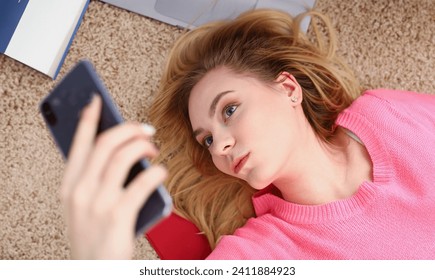 young beautiful woman have a rest lie on the floor hold smartphone in arms nice holiday concept voip telephony Foto Stock