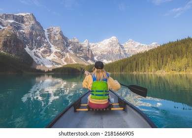 A young blonde woman paddles a canoe on the scenic, picturesque glacial Moraine Lake, a popular outdoor tourist destination in Banff National Park, Alberta, Canada in the Rocky Mountains. Foto stock