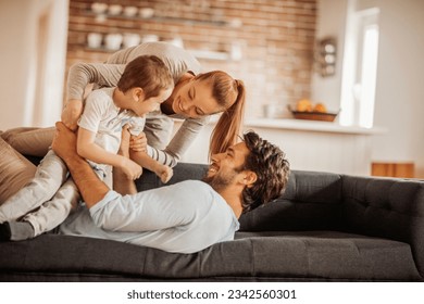 自宅のリビングルームで一緒にソファに遊ぶ若い家族の写真素材