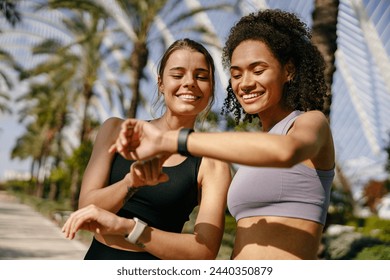 Стоковая фотография: Young fit women looking at smartwatch and counting calories burned. Healthy life concept 