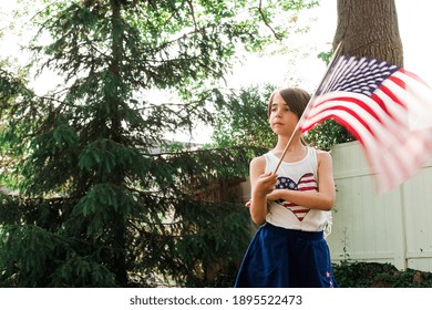 Young girl holding an Amercian flag in backyard Stock Photo